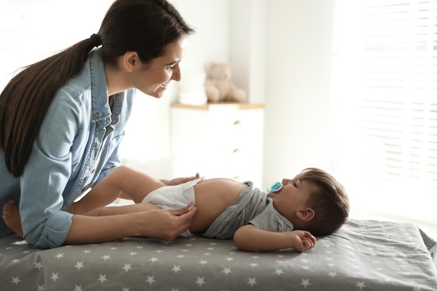 Mère changeant la couche de bébé sur la table à la maison