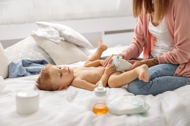 Mère changeant sa couche de bébé sur le lit