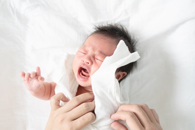 Mère changer de vêtements de bébé nouveau-né qui pleure.