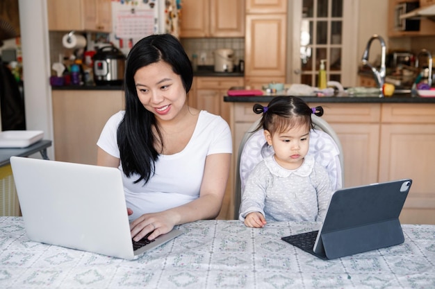 Une mère chinoise asiatique et sa fille travaillent ensemble sur un ordinateur portable.
