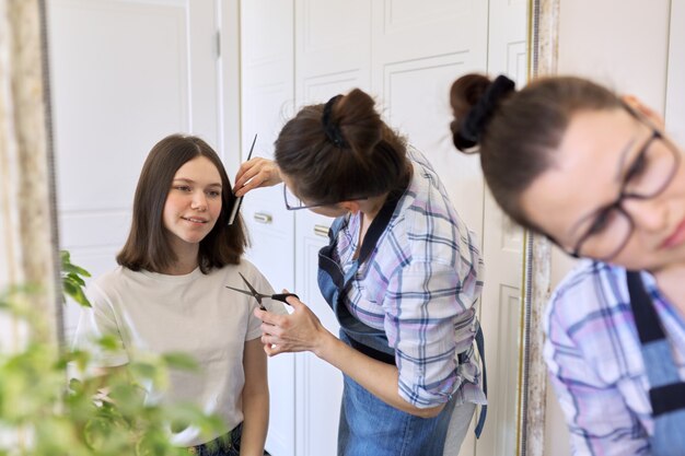 Mère coupant les cheveux à sa fille adolescente, beauté et soins à la maison.