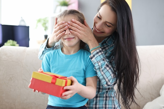 Mère Couvrant Les Yeux De Sa Fille Avec Ses Mains Petite Fille Tenant Une Boîte Avec Un Cadeau