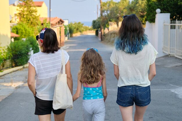 Mère et deux filles adolescente et plus jeune marchant ensemble main dans la main