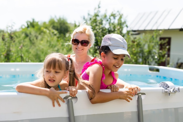 Mère et deux filles jouant dans l'eau de la piscine. Une femme et deux filles s'amusent dans la piscine de la maison en éclaboussant de l'eau et souriant