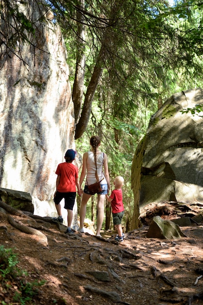 Mère et deux petits fils se tiennent près des rochers dans la forêt. Loisir