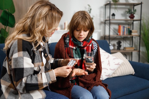 Mère donnant la pilule à sa fille avec la grippe Femme prenant soin d'une fille malade