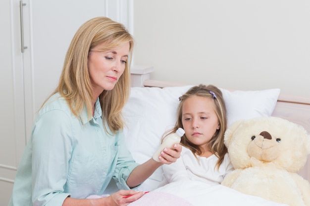 Mère donnant à sa fille la médecine contre la toux