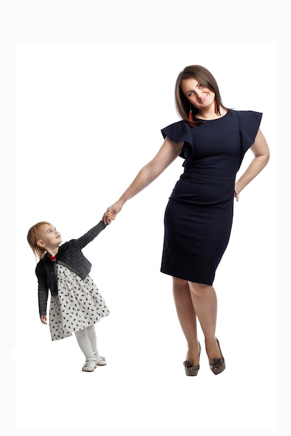 Une mère élégante avec sa petite fille se tiennent la main et sourient. Amour et tendresse. Pleine hauteur. Isolé sur fond blanc. Verticale.