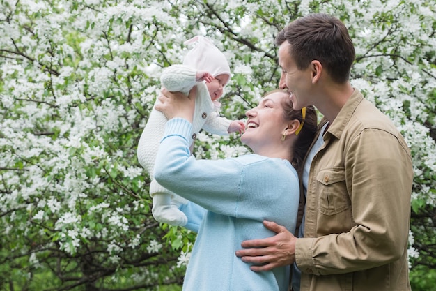 Mère élève sa petite fille souriante et son père étreignant sa femme