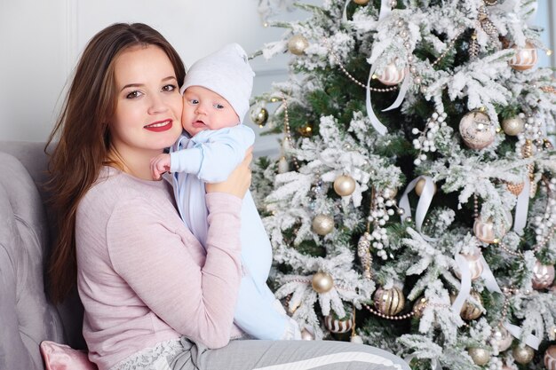 Mère embrassant le bébé près de l'arbre de Noël