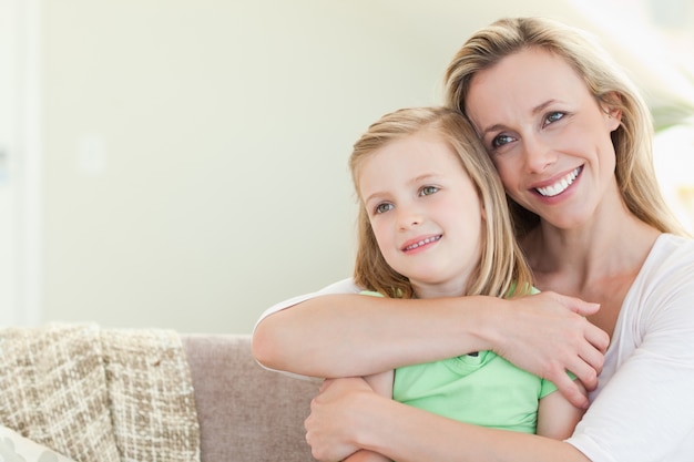 Mère embrassant la fille sur le canapé