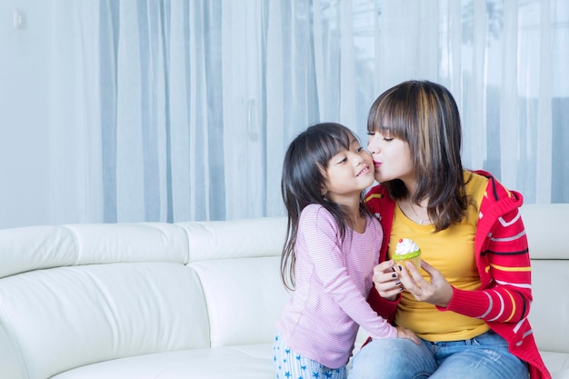 Mère embrassant sa fille tout en obtenant un petit gâteau