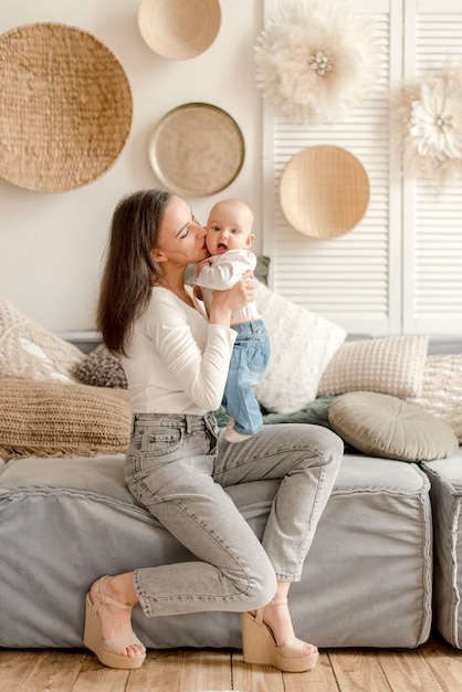 Mère embrassant son bébé assis sur le canapé