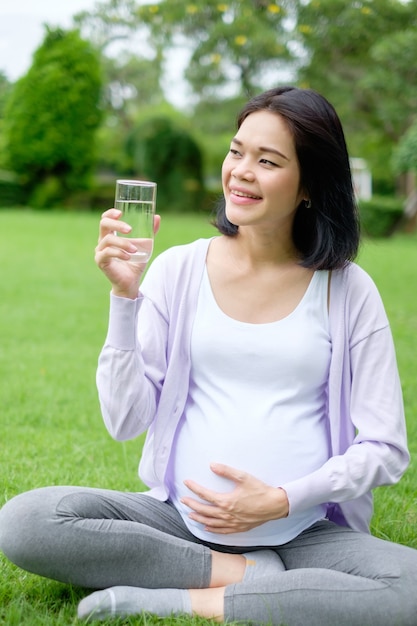 Une mère enceinte est assise en tenant un verre d'eau potable pour une bonne santé.