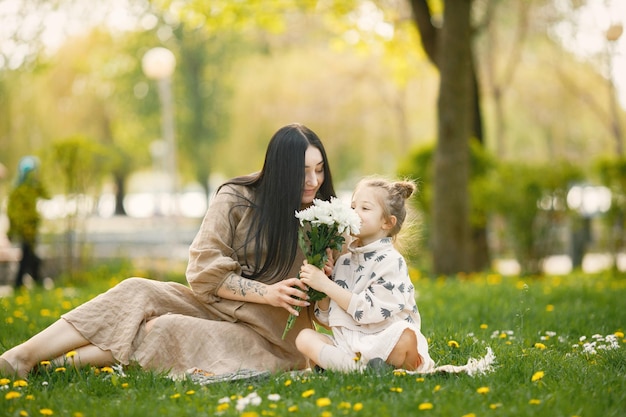 Mère enceinte et sa petite fille assise sur une herbe dans un parc