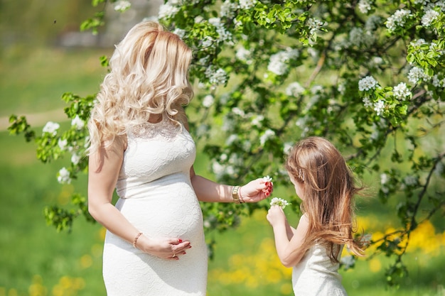 Une mère enceinte et sa petite fille s'amusent en plein air. Portrait de famille