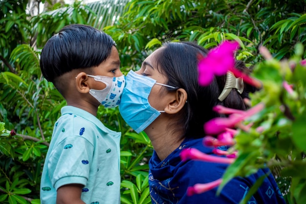 La mère et l'enfant asiatiques s'embrassent et s'aiment tout en portant des masques de sécurité Concept d'hygiène et de sécurité Maman et l'enfant ont des moments heureux dans le jardin verdoyant