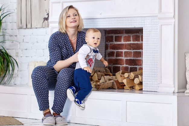 La mère avec l'enfant en bas âge s'assied dans le salon près de la cheminée