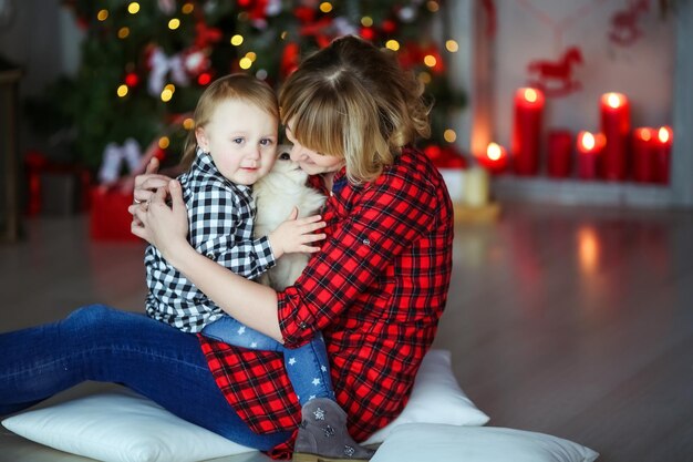 Mère avec enfant en chemises à carreaux sur le fond des bougies rouges de Noël et de l'arbre de Noël.