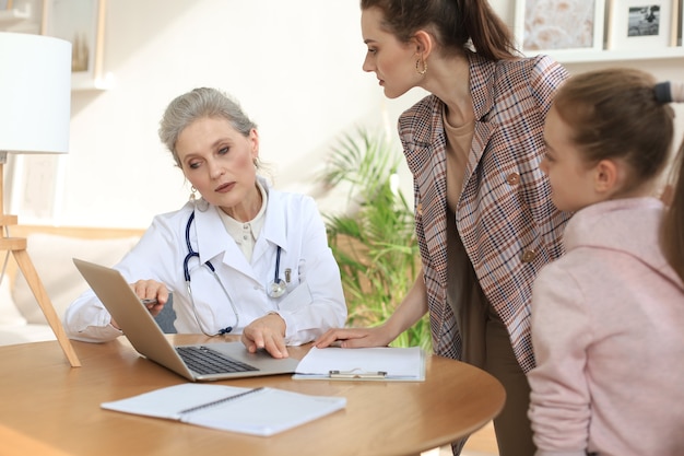 Mère et enfant dans le bureau du médecin rencontrant le pédiatre, ils sont assis au bureau à l'hôpital.