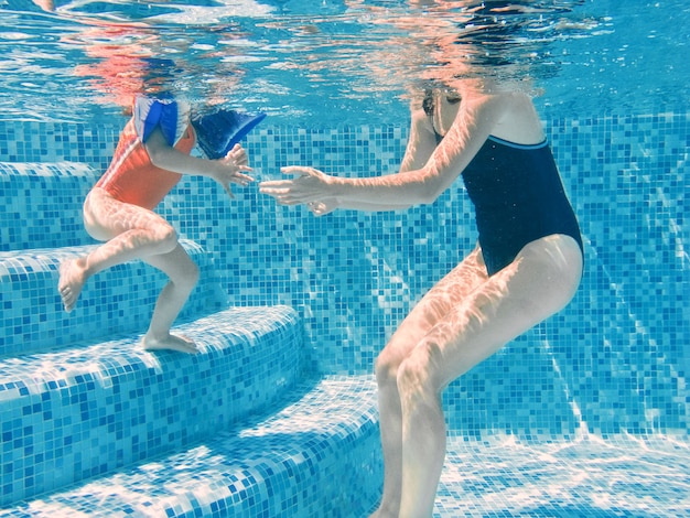 Mère et enfant dans la piscine jambes sous-marines de la femme et de l'enfant dans l'eau de la piscine vacances en famille