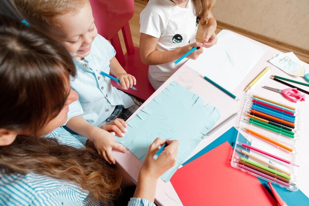 Une mère avec un enfant est assise à table et fait ses devoirs. L'enfant apprend à la maison. Enseignement à domicile.