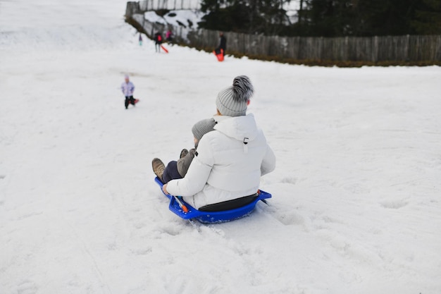 Une mère avec un enfant faisant de la luge dans la neige