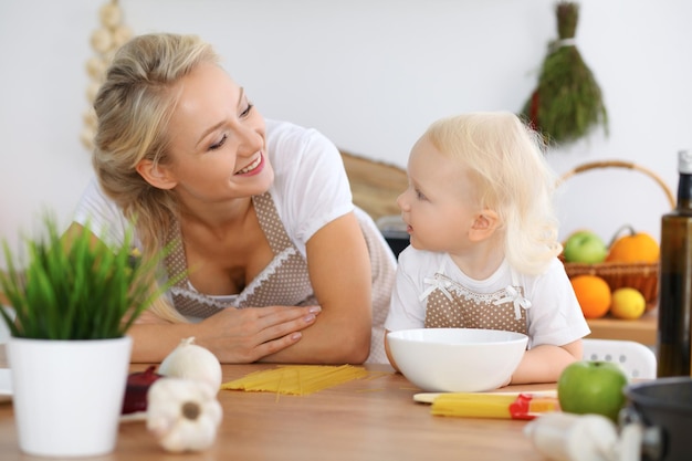 Mère et enfant fille cuisinant des pâtes ou de la salade pour le petit-déjeuner. Concept de famille heureuse dans la cuisine.