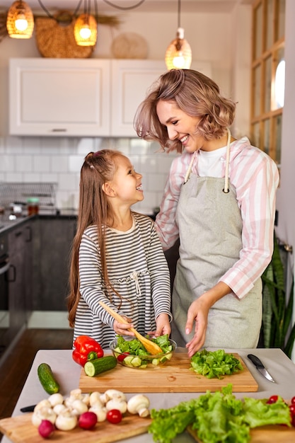 Mère et enfant fille préparer des aliments sains pour la famille, salade végétalienne à base de légumes frais, mélanger