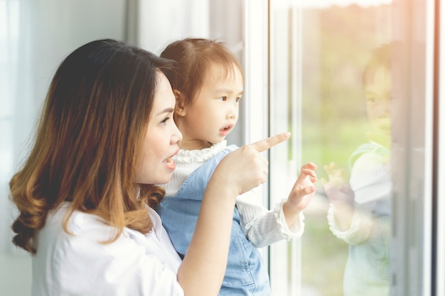 Mère et enfant fille regardent par la fenêtre.