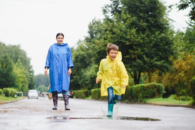 Mère et enfant jouant sous la pluie, portant des bottes et des imperméables