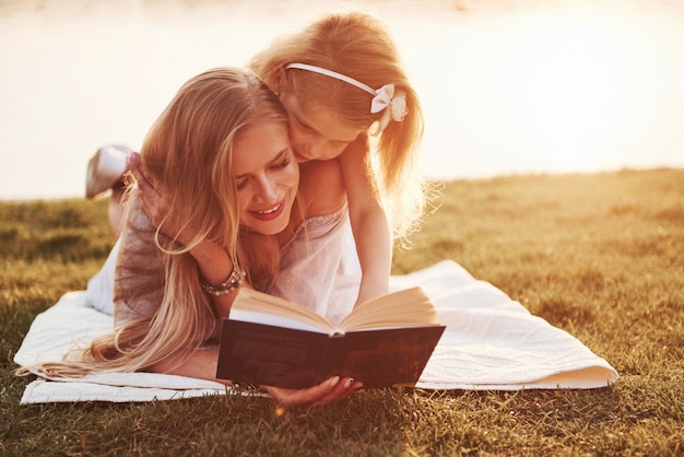 Mère avec un enfant lit un livre sur l'herbe