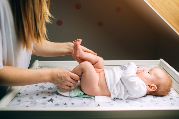 Mère et enfant nouveau-né dans la pépinière. Maman fait des exercices pour l'enfant. Dysplasie et tonus musculaire