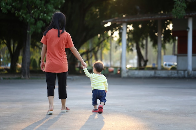 Mère et enfant tenant une main pour marcher dans le parc.