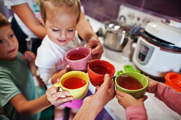 Une mère avec des enfants boit de la compote à la cuisine, des moments heureux pour les enfants.