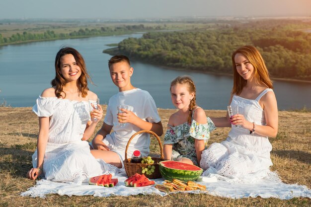 La mère et les enfants heureux ont un pique-nique festif sur la colline verte