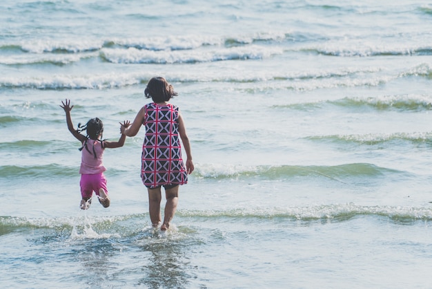 Mère et enfants marchant et runnes sur mer au coucher du soleil