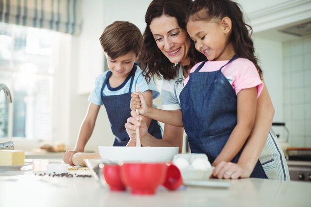 Mère et enfants mélangeant la pâte lors de la préparation des cookies