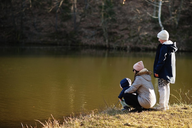 Mère avec enfants pêchant avec un bâton en fourrière au parc du début du printemps