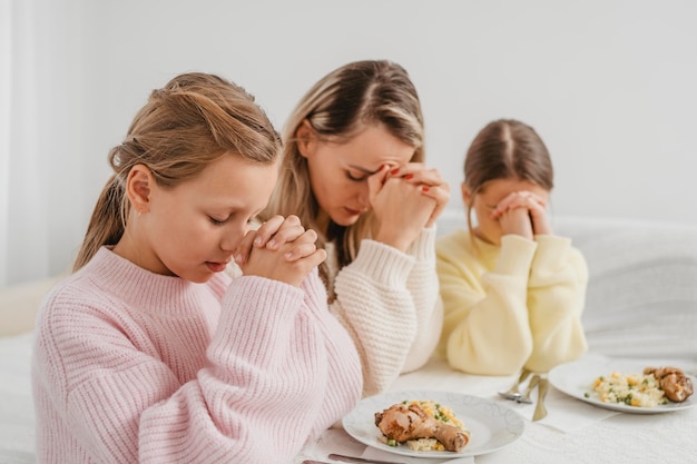 Mère et enfants priant à table