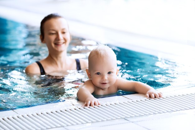 Mère enseignant à bébé à nager Portrait d'un charmant enfant de 11 mois en classe dans une piscine