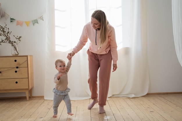 Mère enseignant à promener son petit bébé Portrait de famille heureuse à la maison Concept de première étape de soins