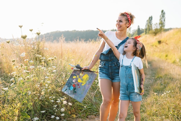 Mère enseigne la peinture à sa fille dans le parc