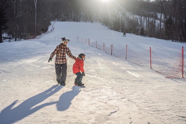 Mère enseigne à son fils le snowboard Activités pour enfants en hiver Sports d'hiver pour enfants