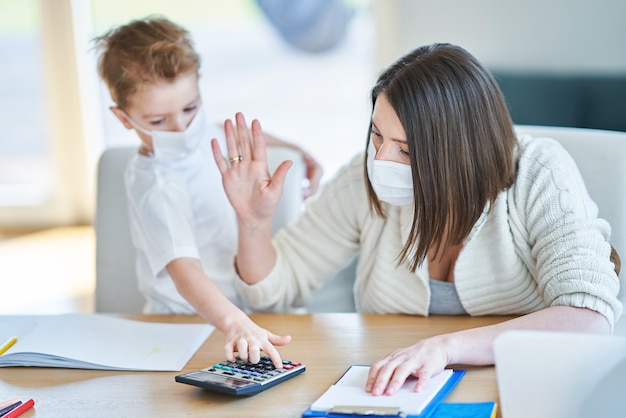 mère épuisée essayant de travailler à la maison et prenant soin de son fils pendant la pandémie de coronavirus