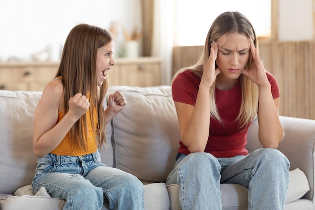 Une mère épuisée et stressée touchant la tête, désespérée par les cris de sa fille