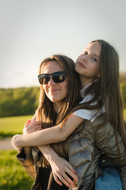 Mère espiègle donnant à sa fille une promenade sur le dos au champ vert