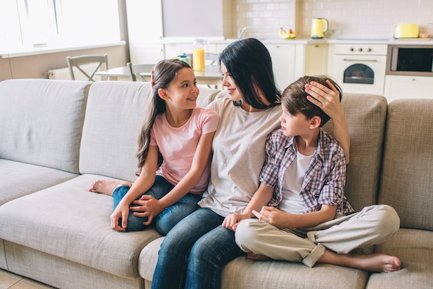 La mère est assise sur le canapé avec ses enfants