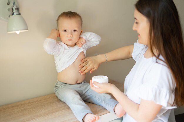 la mère étale de la crème sur les joues de l'enfant pour les allergies et la dermatite.