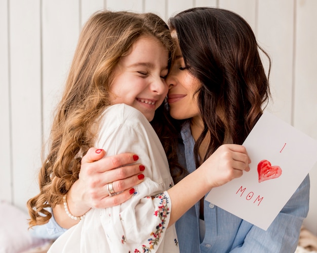 Mère étreignant fille avec carte de voeux